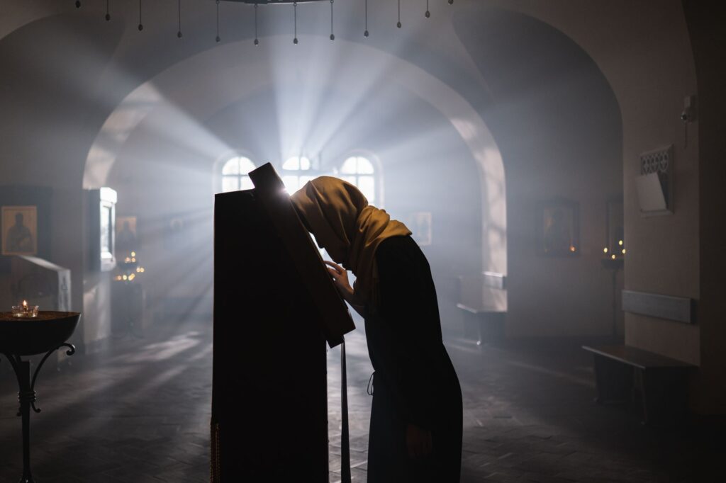 A woman in a shawl prays in a sunlit church, evoking peace and spirituality