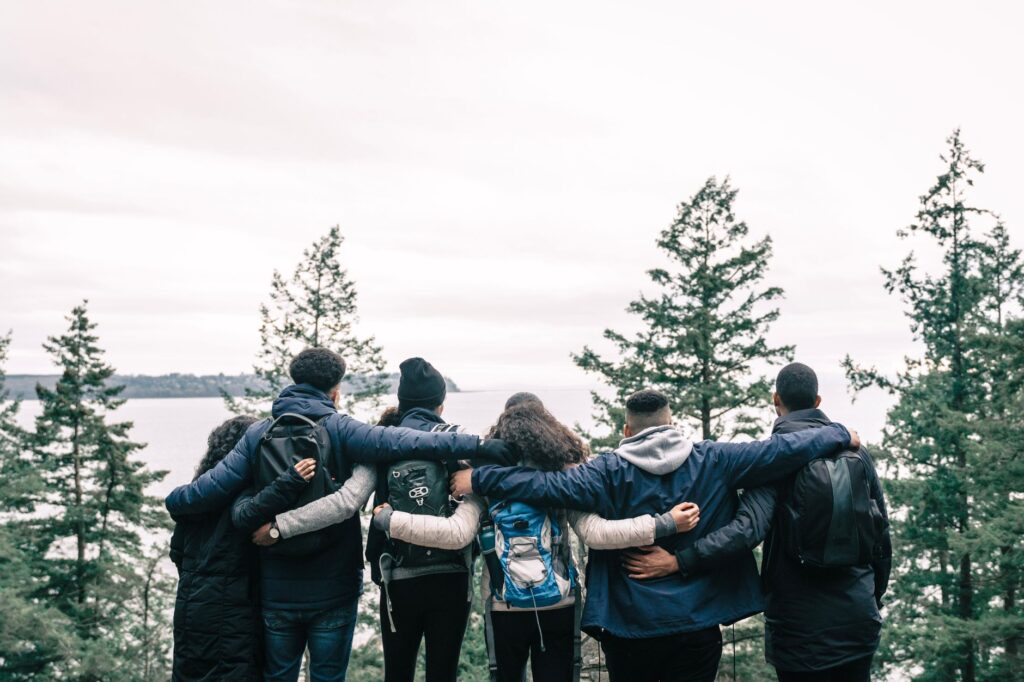 Friends embrace while standing on a scenic cliff, symbolizing unity and adventure