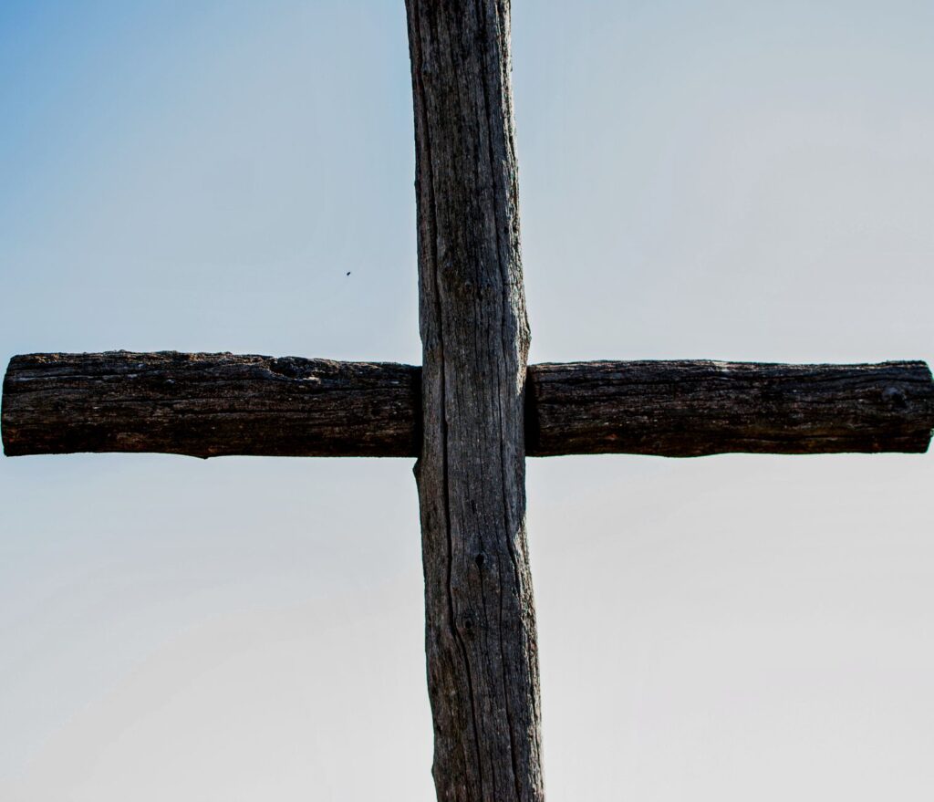 Wooden cross against a clear blue sky, symbolizing Christianity and spirituality